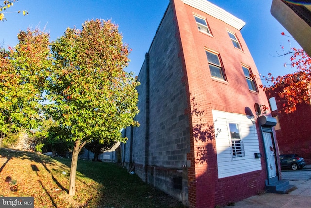 view of home's exterior with brick siding and a lawn