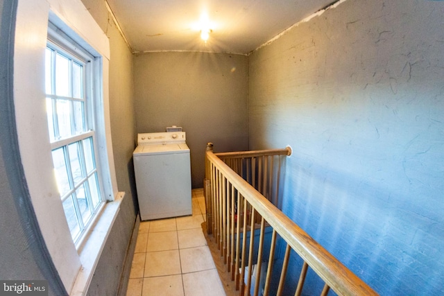 hall featuring washer / dryer, an upstairs landing, and light tile patterned floors