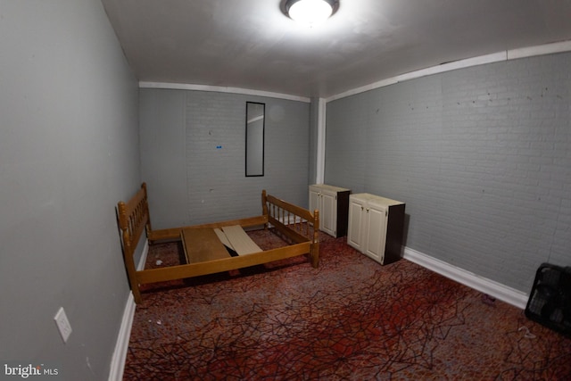 interior space featuring baseboards and brick wall