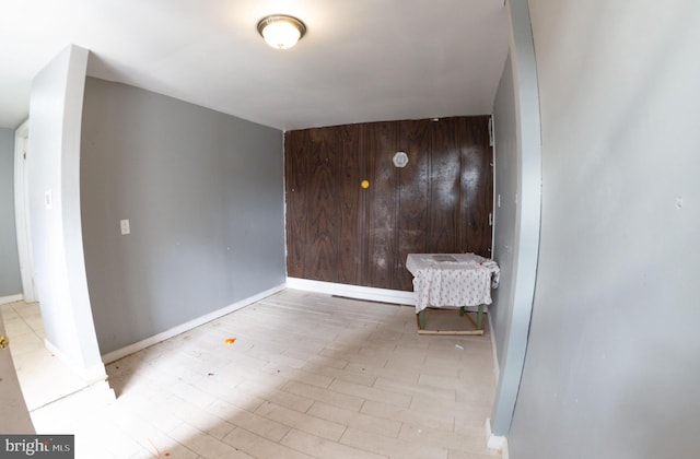 empty room with wood walls, wood finished floors, and baseboards