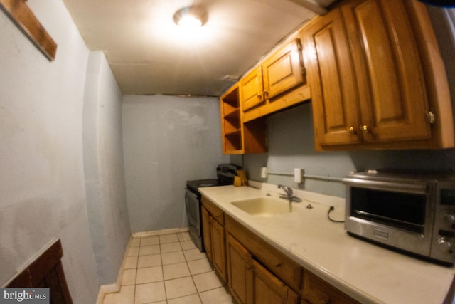 kitchen featuring light tile patterned floors, a toaster, stainless steel electric range, light countertops, and a sink