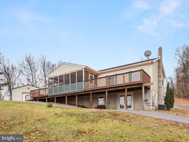 rear view of property with a sunroom, central AC unit, and a lawn