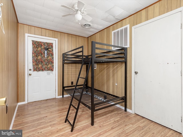 bedroom featuring wooden walls and light hardwood / wood-style flooring