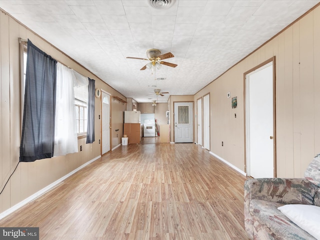 unfurnished living room featuring light hardwood / wood-style flooring, ceiling fan, and wooden walls