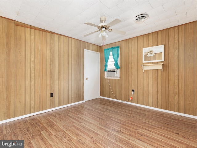 unfurnished room featuring cooling unit, hardwood / wood-style flooring, ceiling fan, and wooden walls