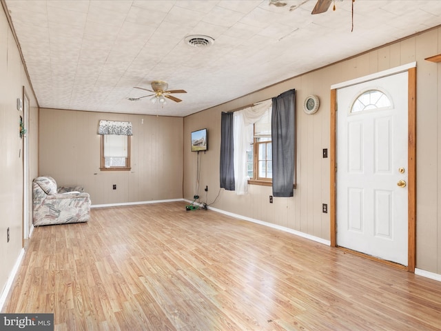 entrance foyer featuring wooden walls, ceiling fan, light hardwood / wood-style floors, and a wealth of natural light