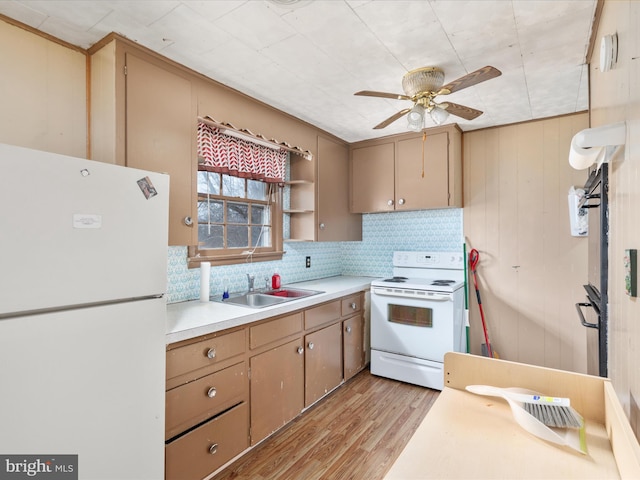 kitchen with white appliances, ceiling fan, wooden walls, sink, and light hardwood / wood-style floors