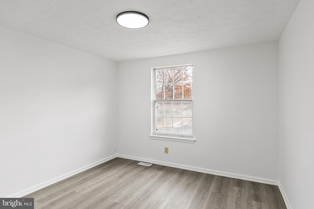 spare room with a textured ceiling and light hardwood / wood-style flooring