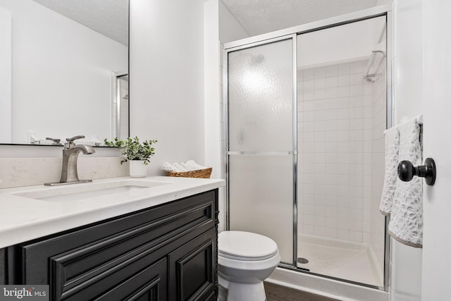 bathroom with walk in shower, vanity, a textured ceiling, and toilet