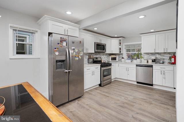 kitchen featuring stainless steel appliances, light hardwood / wood-style floors, and white cabinets