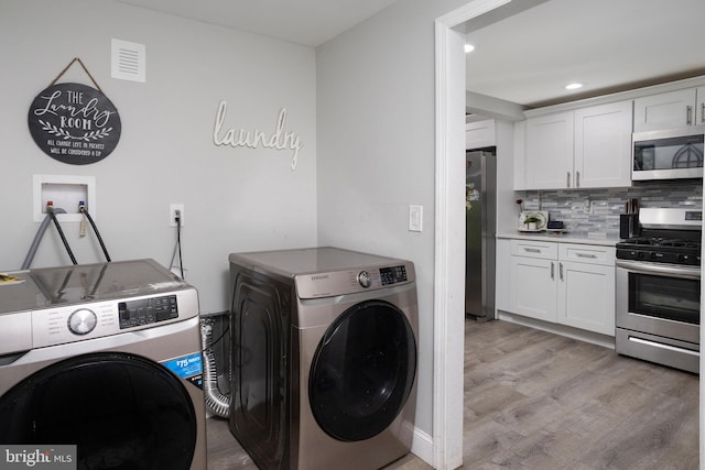 washroom featuring washer and clothes dryer and light wood-type flooring