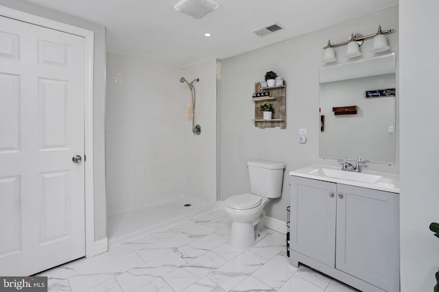 bathroom featuring vanity, a tile shower, and toilet