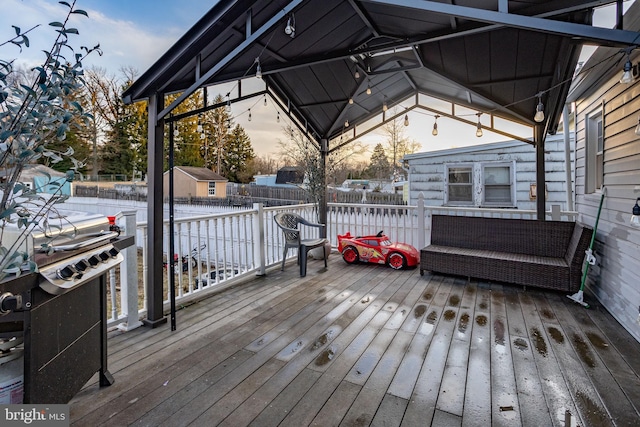 deck at dusk featuring a gazebo and a storage unit