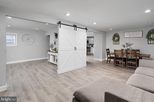 living room featuring a barn door and light hardwood / wood-style floors