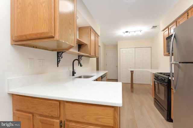 kitchen with light brown cabinetry, light wood-type flooring, stainless steel appliances, and sink