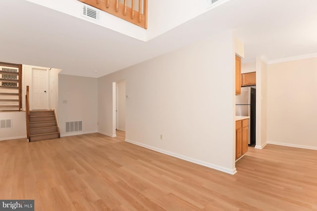 unfurnished living room featuring light wood-type flooring and crown molding