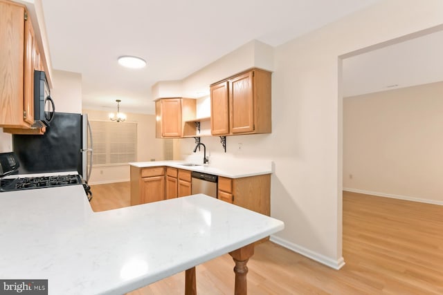 kitchen featuring sink, stainless steel dishwasher, kitchen peninsula, light hardwood / wood-style floors, and decorative light fixtures