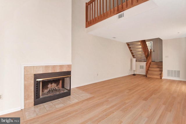 unfurnished living room featuring a tile fireplace and hardwood / wood-style floors