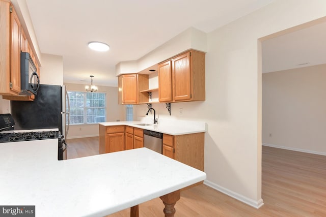 kitchen featuring kitchen peninsula, pendant lighting, light wood-type flooring, and black appliances