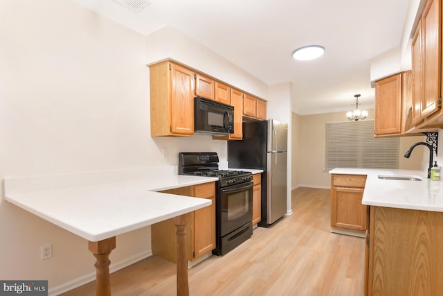 kitchen with pendant lighting, black appliances, sink, light hardwood / wood-style floors, and kitchen peninsula