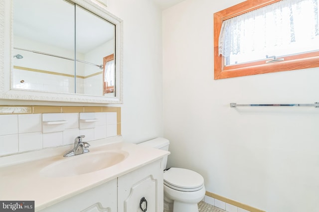 bathroom with tile patterned flooring, vanity, toilet, and backsplash