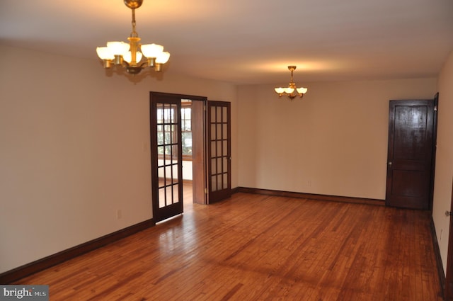 unfurnished room with hardwood / wood-style flooring, french doors, and a notable chandelier