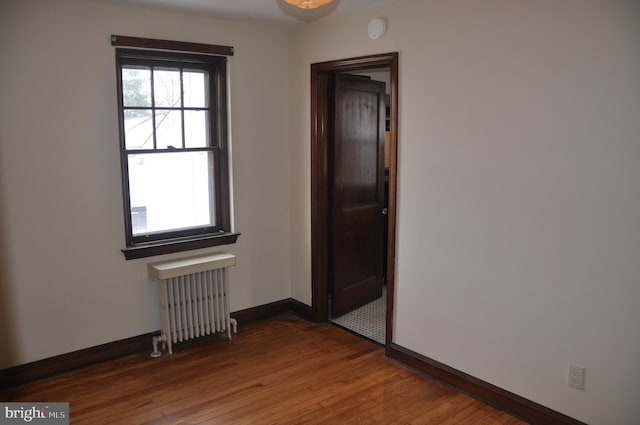 unfurnished room featuring wood-type flooring and radiator heating unit