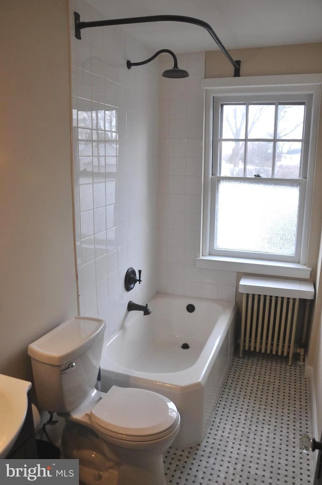 bathroom featuring tiled shower / bath combo, toilet, and radiator