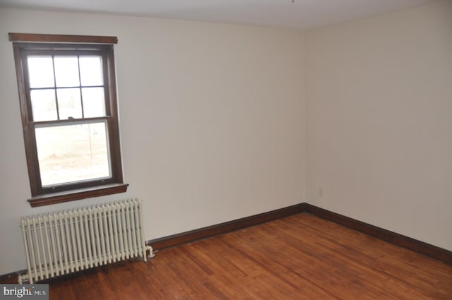 empty room featuring dark hardwood / wood-style flooring and radiator heating unit