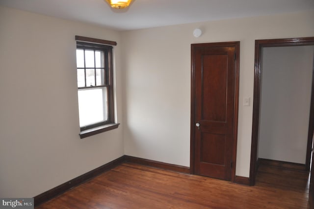 unfurnished room with dark wood-type flooring