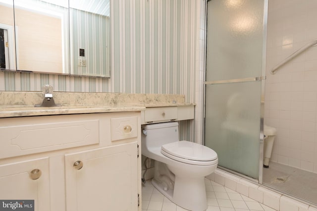 bathroom with tile patterned flooring, vanity, a shower with door, and toilet