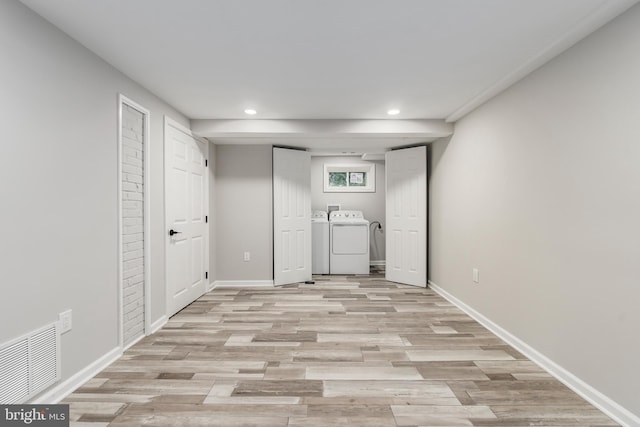 clothes washing area with washer and dryer and light wood-type flooring