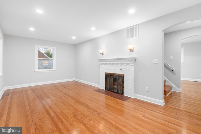 unfurnished living room featuring light wood-type flooring and a brick fireplace