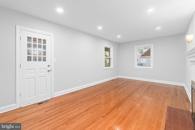 entryway featuring light hardwood / wood-style floors and a brick fireplace