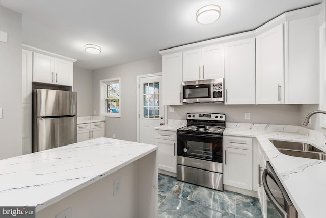 kitchen with light stone counters, sink, white cabinetry, and stainless steel appliances