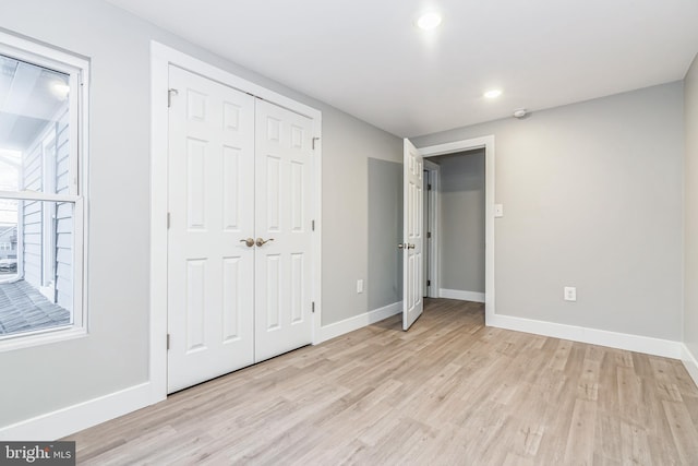 unfurnished bedroom with light hardwood / wood-style flooring and a closet