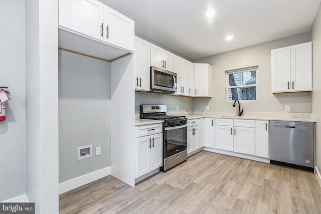 kitchen with sink, light wood-type flooring, white cabinetry, and stainless steel appliances