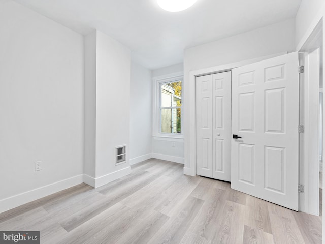 unfurnished bedroom with a closet and light wood-type flooring