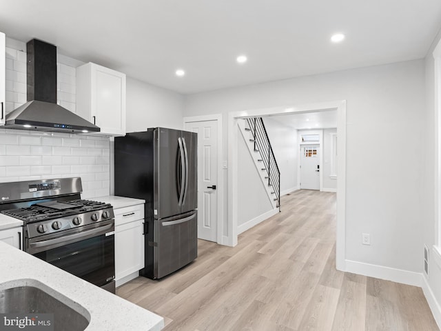 kitchen featuring white cabinets, appliances with stainless steel finishes, backsplash, and wall chimney exhaust hood