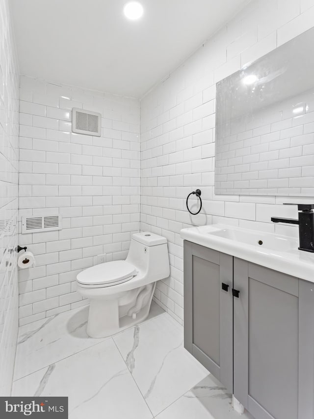 bathroom with vanity, toilet, and tile walls