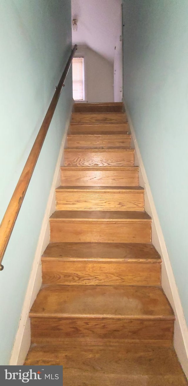 staircase featuring hardwood / wood-style flooring and lofted ceiling