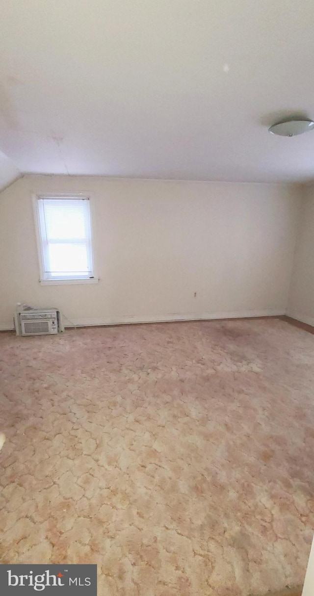 spare room with a wall mounted air conditioner and vaulted ceiling