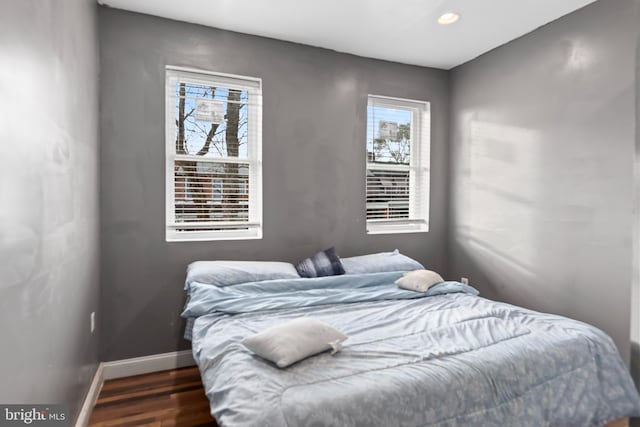 bedroom with dark hardwood / wood-style floors and multiple windows