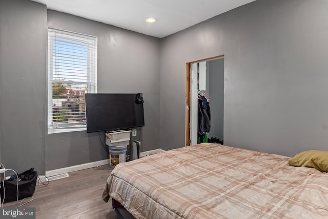 bedroom with multiple windows, a closet, and hardwood / wood-style floors