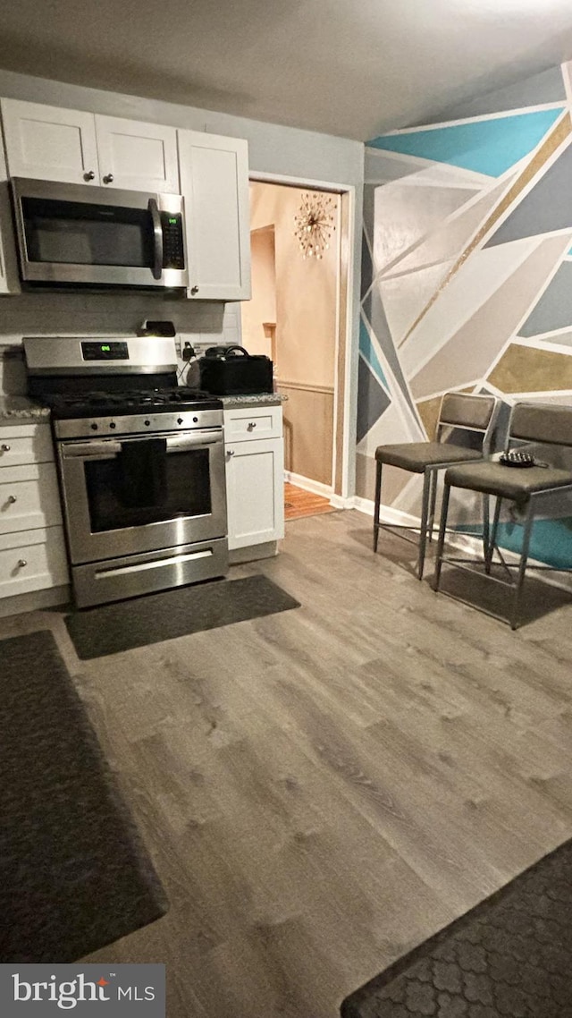 kitchen with hardwood / wood-style flooring, white cabinets, and appliances with stainless steel finishes