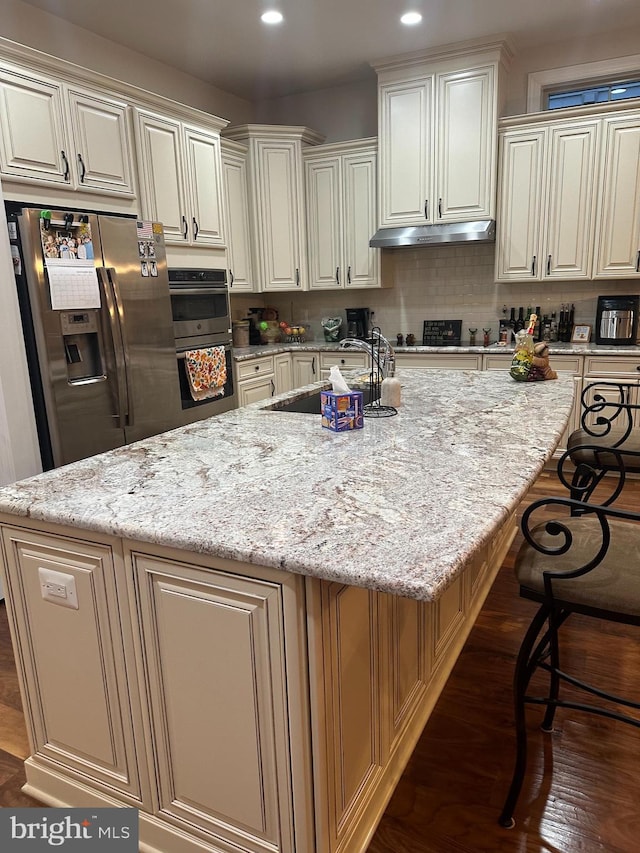 kitchen with light stone countertops, ventilation hood, and a spacious island