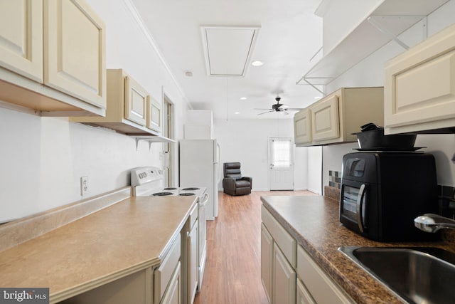 kitchen with white appliances, sink, light wood-type flooring, ornamental molding, and cream cabinetry