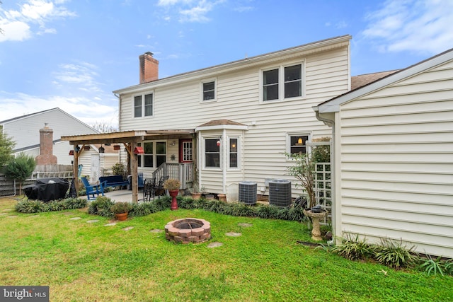rear view of property featuring a lawn, cooling unit, a patio area, and an outdoor fire pit