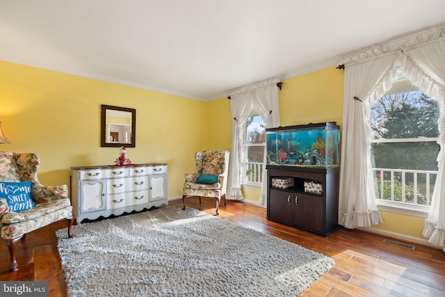 sitting room with hardwood / wood-style flooring, crown molding, and a wealth of natural light
