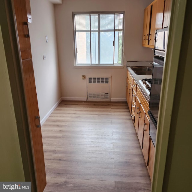 kitchen featuring oven, light hardwood / wood-style floors, and radiator